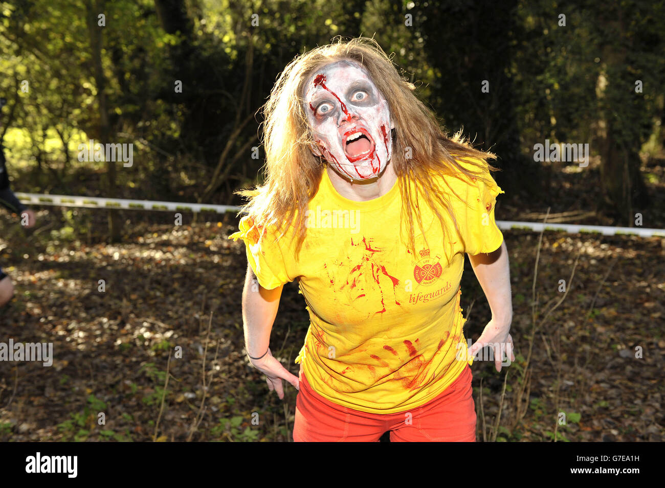 Während des Zombie Evacuation Race im Milton Country Park in Cambridge erscheint ein „Zombie“ aus dem Wald. Stockfoto