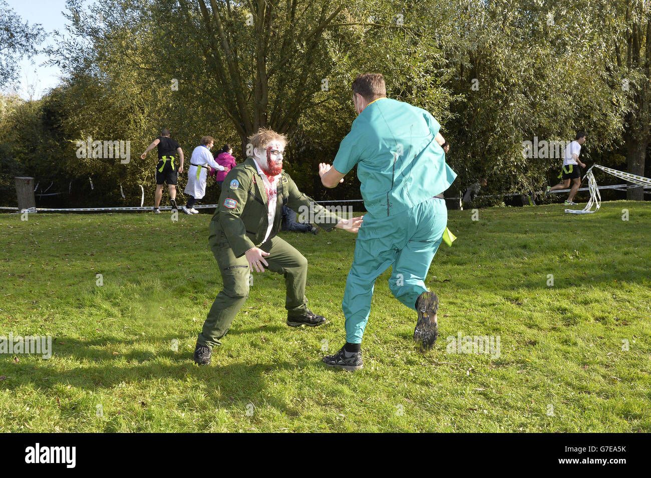 Ein Konkurrent versucht, einem 'Zombie' während des Zombie Evacuation Race im Milton Country Park in Cambridge auszuweichen. Stockfoto
