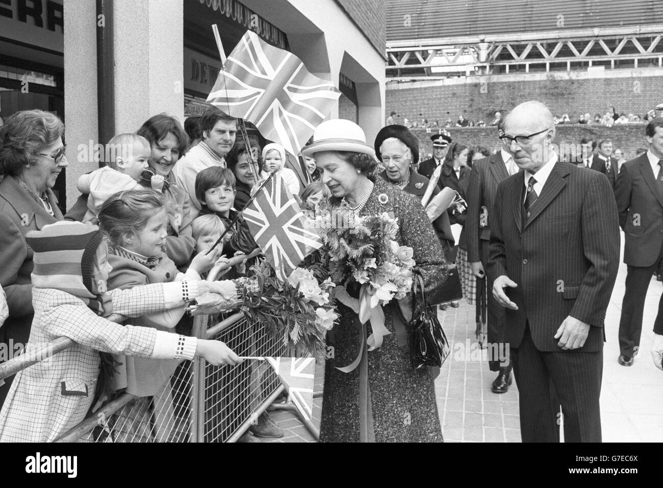 Königin Elizabeth II. Erhält Blumen von jungen Bewunderern bei einem Besuch im King Edward Court Einkaufszentrum in Windsor. Stockfoto