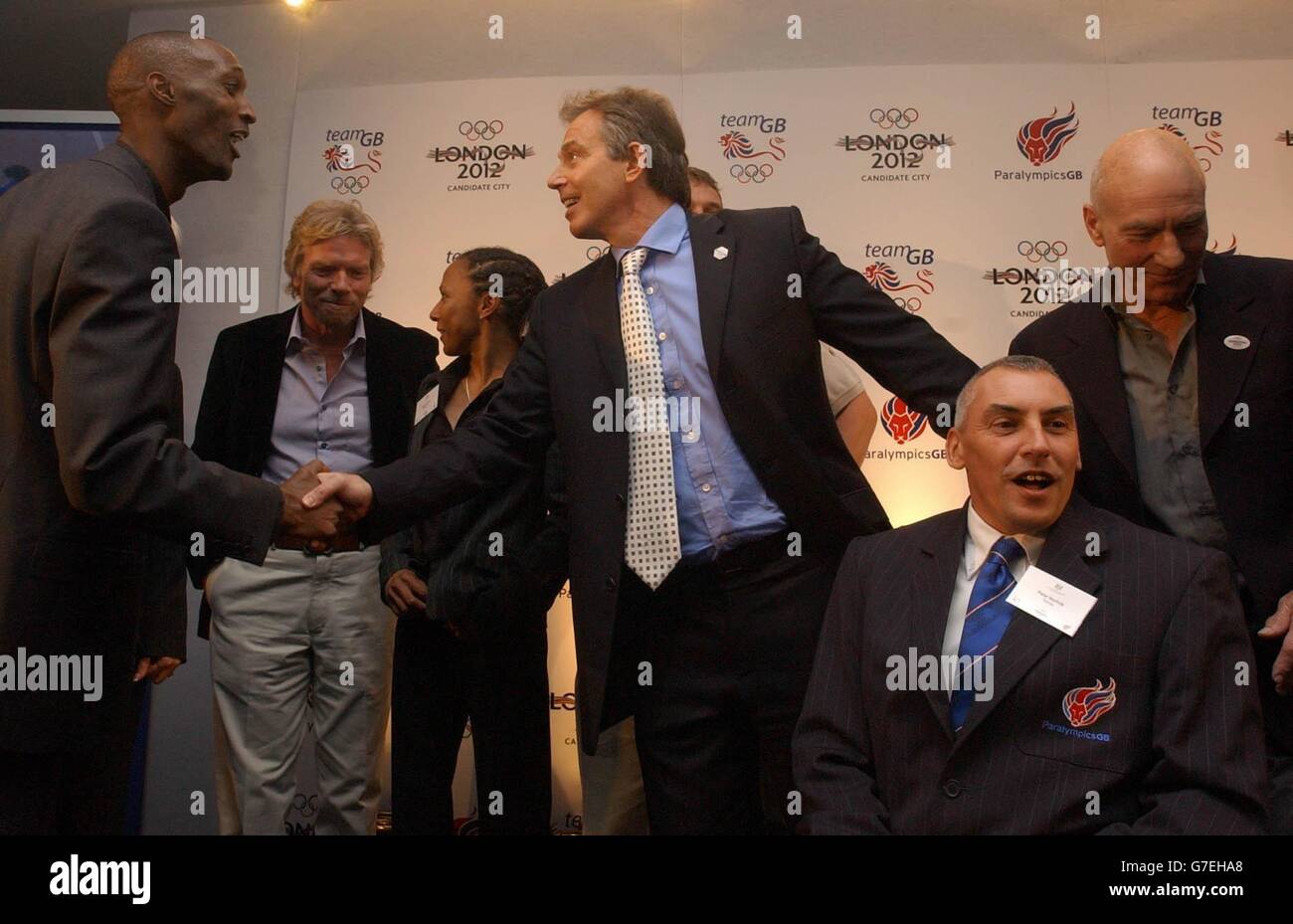 Der britische Premierminister Tony Blair tritt bei einem Empfang der olympischen und paralympischen Athleten, die an den diesjährigen Olympischen Spielen in Athen teilgenommen haben, veranstaltet von Downing Street, im Lords Cricket Ground, London, mit Athleten und Unterstützern der Olympischen Bewerbung 2012 in London auf die Bühne, darunter Richard Branson und Kelly Holmes. Stockfoto