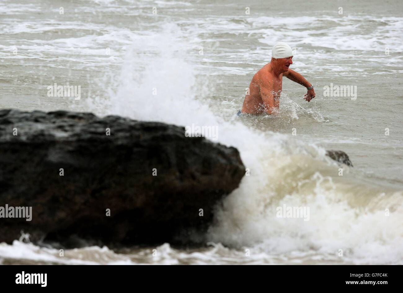 Ein Mann geht trotz der widrigen Wetterbedingungen in Portmarnock, Dublin, schwimmen. Stockfoto