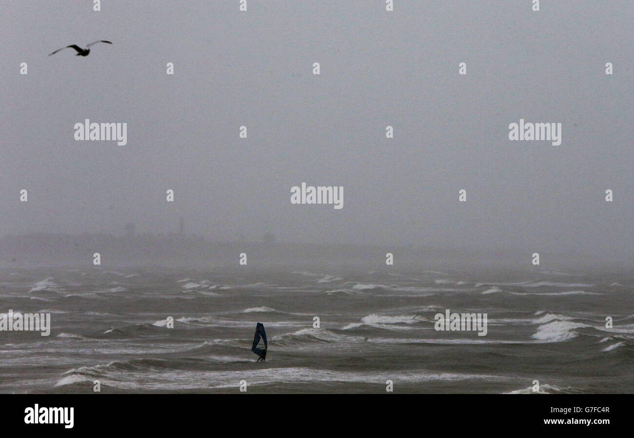 Ein Windsurfer macht das Beste aus den widrigen Wetterbedingungen in Portmarnock, Dublin. Stockfoto