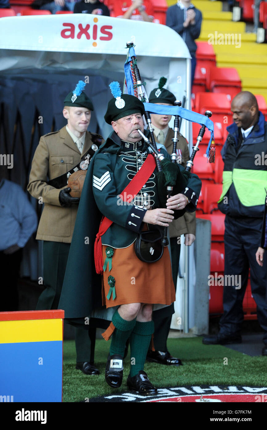 Ein Dudelsackläufer führt zwei Soldaten aus den Londoner Iren heraus Gewehre mit dem Fußball vor dem Spiel Stockfoto