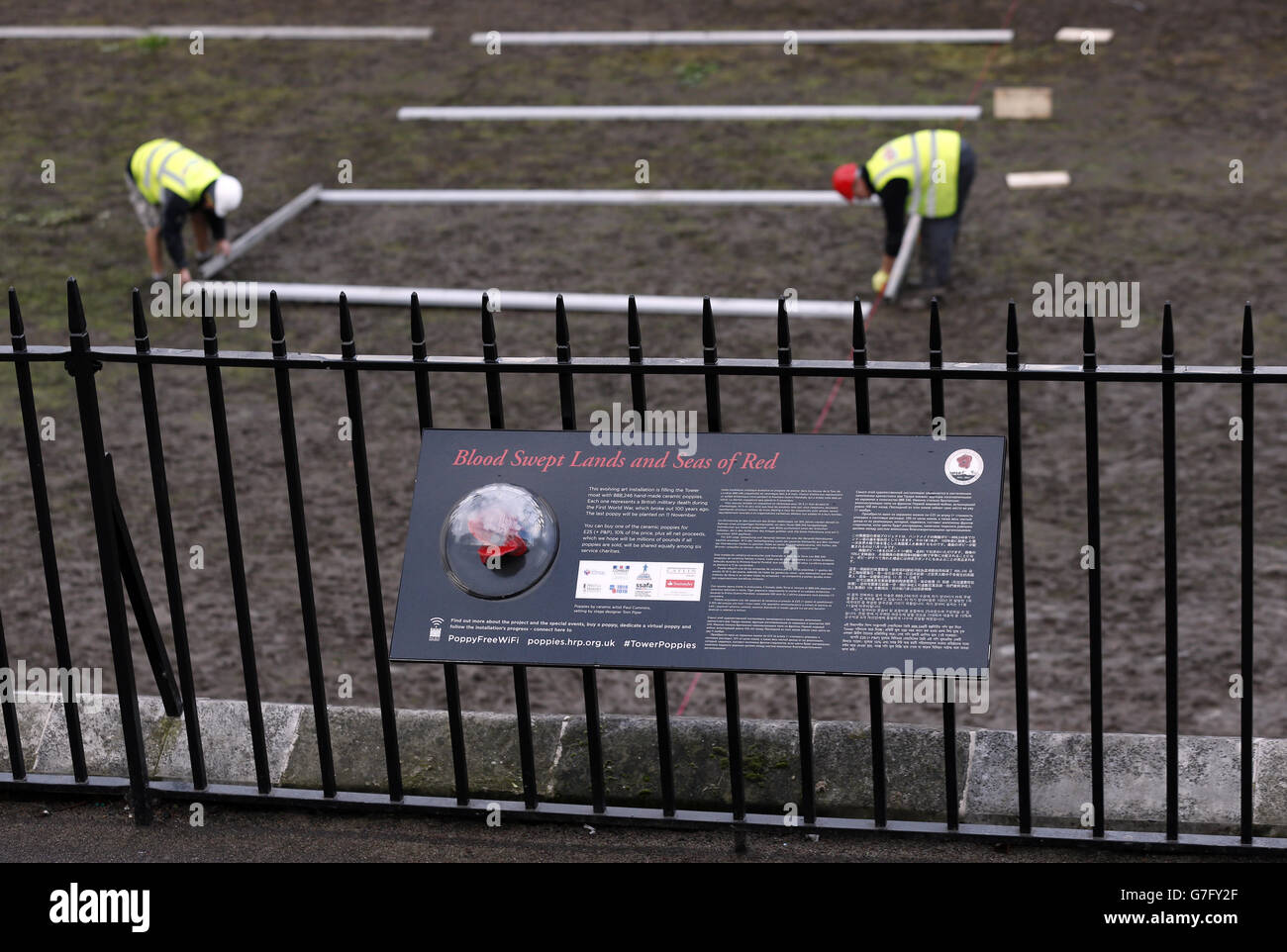 Eine Plakette, die die Installation Blood Swept Lands and Seas of Red vor dem Tower of London erklärt, wo Freiwillige geholfen haben, die Keramikmohn zu demontieren, die Teil des Stücks von Paul Cummins und Tom Piper waren. Stockfoto