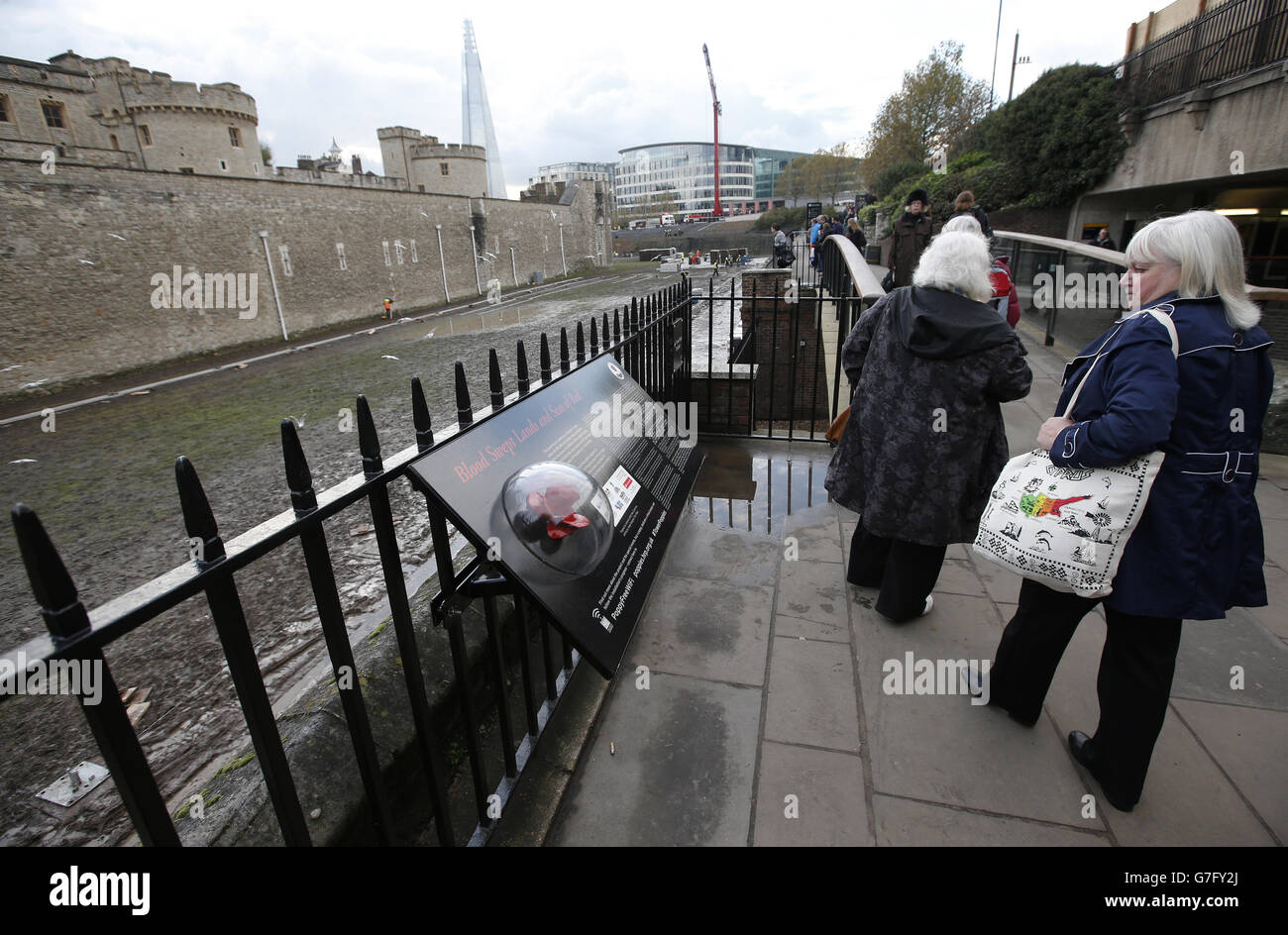 Die Mitglieder der Öffentlichkeit laufen am Tower of London vorbei, wo Freiwillige geholfen haben, die Keramikmohn, die Teil der Installation, Blood Swept Lands und Seas of Red waren, zu demontieren. Stockfoto