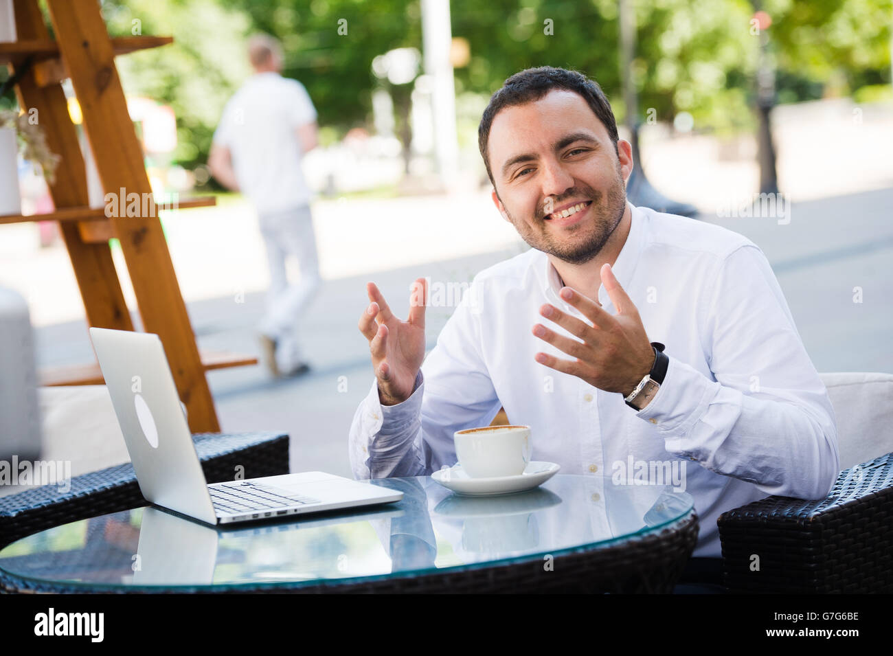 Hübscher junger Mann lächelnd und Kaffeetrinken in einem Restaurant am Meer. Er ist glücklich, Blick in die Kamera Stockfoto