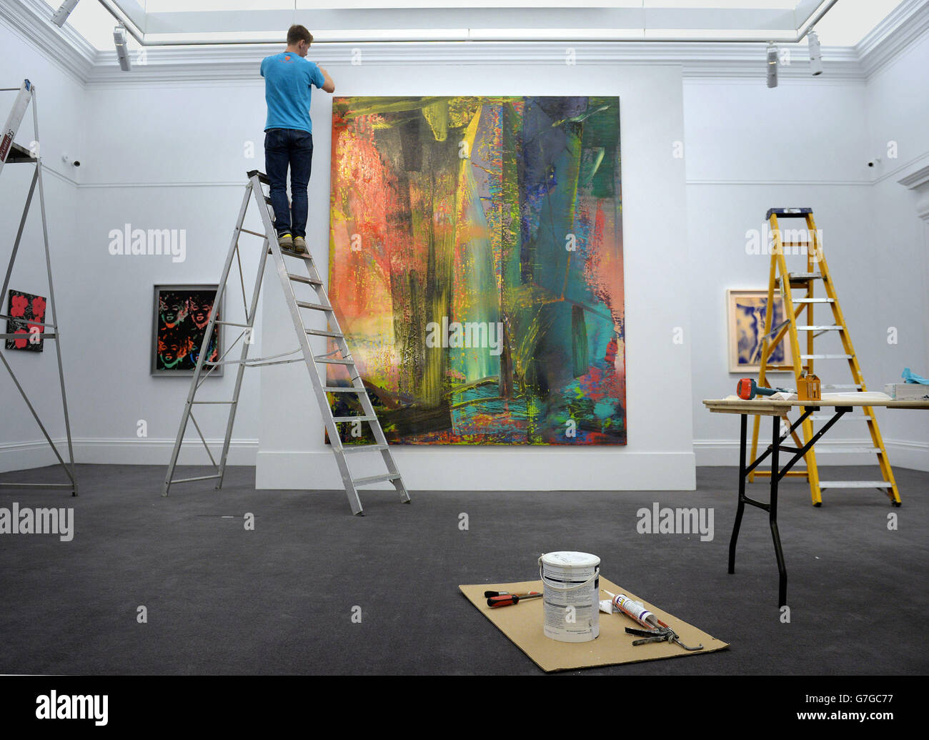 Ein Techniker passt die Beleuchtung über Gerhard Richters abstraktes Bild (schätzungsweise 14-20 Millionen) vor der Vorschau für den bevorstehenden Verkauf zeitgenössischer Kunst in Sothebys Auktionshaus in London an. Stockfoto