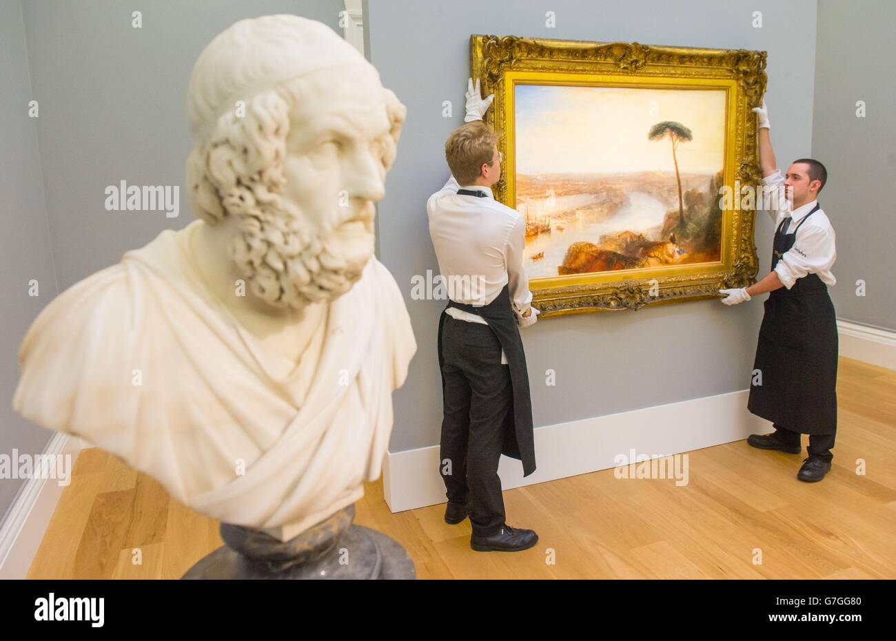 Sothebys Mitarbeiter mit dem Gemälde „Rome, from Mount Aventine“ von William Turner, das neben einer Marmorbüste von Homer von Francis Harwood in Sotheby's Galerie in Mayfair, London, zu sehen ist, die Teil ihres „Old Master & British Paintings Evening Sale“ sind. Stockfoto