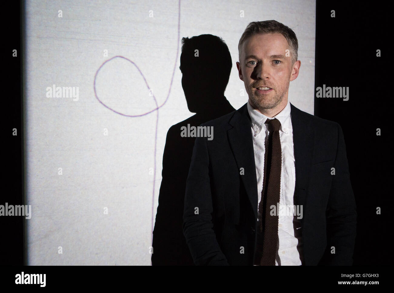 Der in Irland geborene Künstler Duncan Campbell vor seinem Film Stills von Sigmar 2008, der in der Tate Britain im Zentrum Londons den diesjährigen Turner Prize für seine Filmreihe IT for Others gewonnen hat. Stockfoto