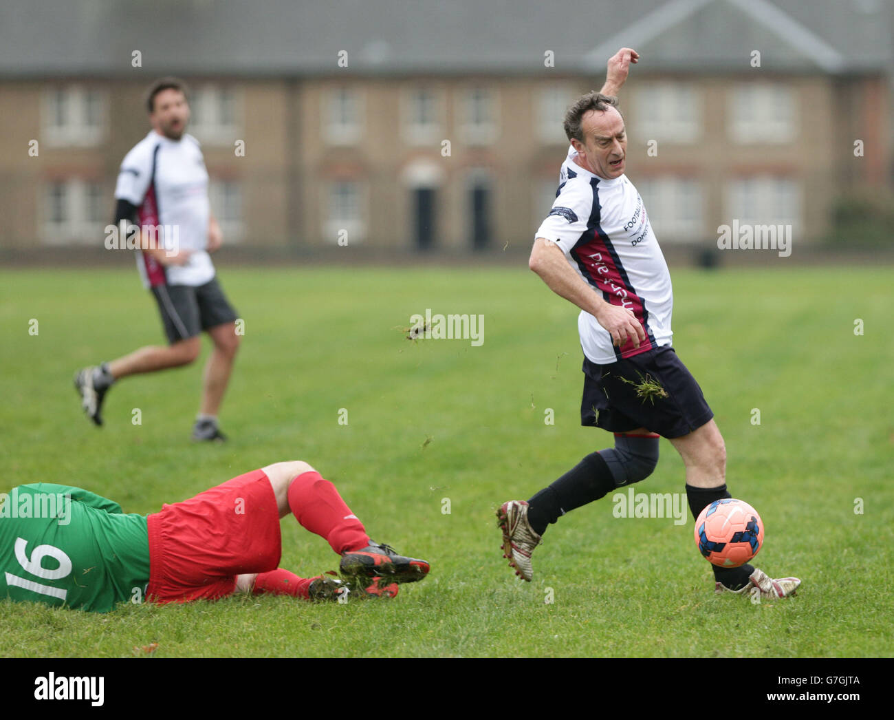 Angus Deayton (rechts) in Aktion während eines Football United gegen häusliche Gewalt gegen Parlamentsmitglieder Wohltätigkeitsfußballspiels im Kensington Palace Gardens, London. Stockfoto