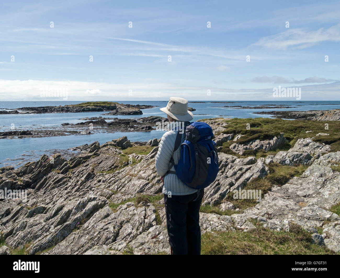 Frau mit Sonnenhut und Rucksack bewundert Atlantik und Ardskenish Küste, auf Insel Colonsay, Scotland, UK. Stockfoto