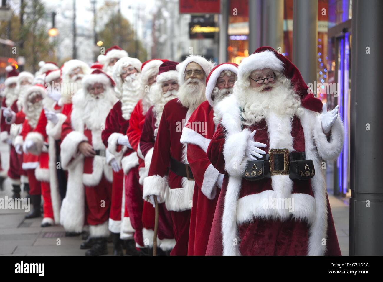 Fünfundzwanzig Santas stehen vor einer Boots-Apotheke in der Oxford Street im Zentrum von London für ihre Wintergrippeimpfung an, um sie während der Weihnachtszeit gut zu halten. Stockfoto
