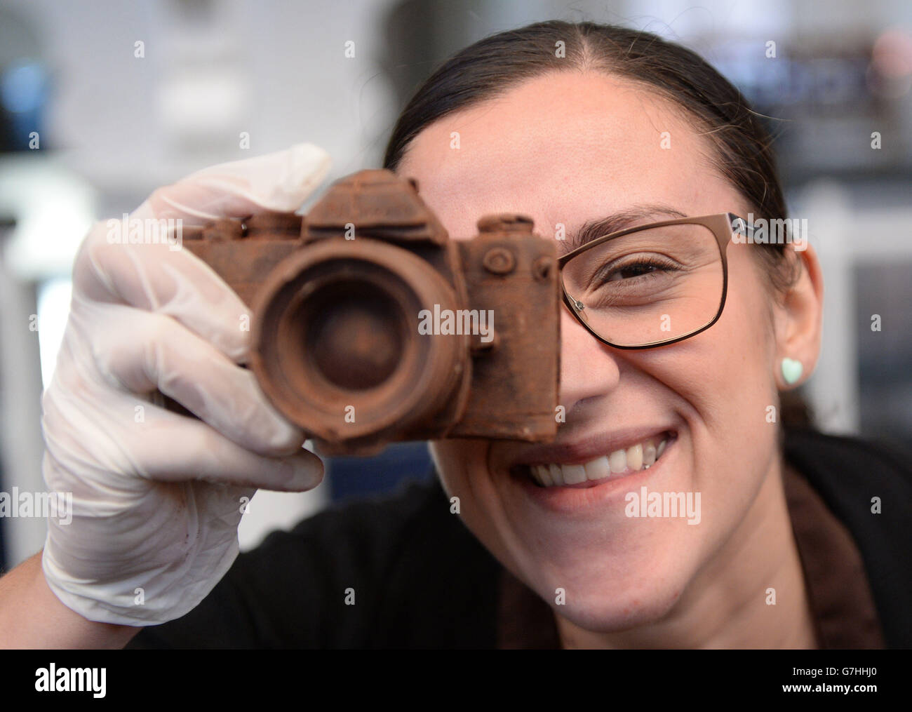 Giovanna Schettini gibt vor, ein Foto mit einer Kamera zu machen, die ausschließlich aus Schokolade besteht, einem der vielen Schokoladenartikel, die auf dem Chocolate Festival in London erhältlich sind. Stockfoto