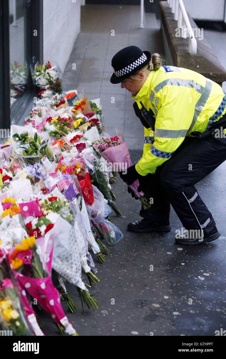 Ein Polizeibeamter stellt Blumen nahe an die Szene auf dem George Square in Glasgow, wo ein Müllwagen mit einer Gruppe von Fußgängern zusammenstieß, die sechs Menschen tot gelassen hat. Stockfoto