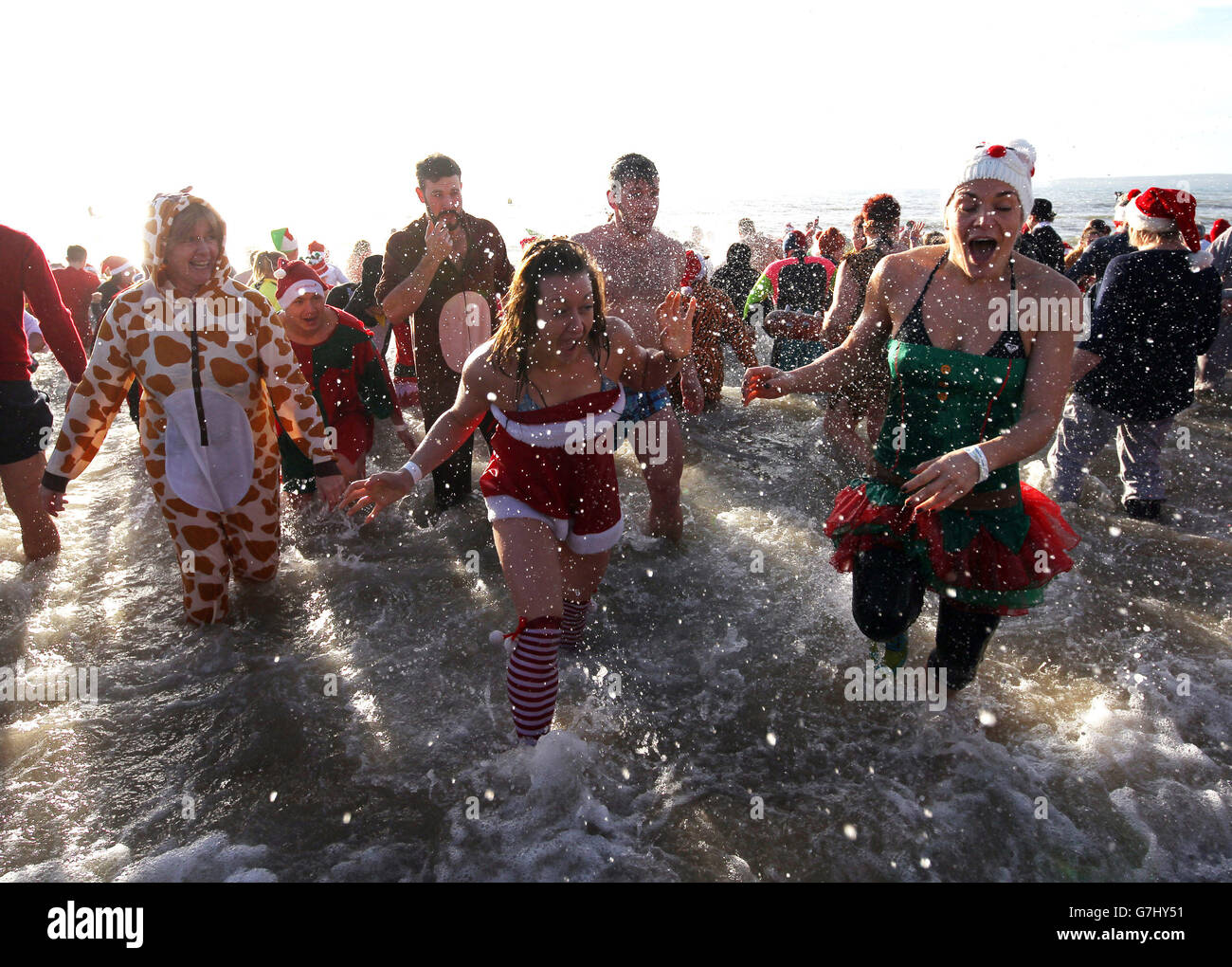 Menschen in Fancy Dress an den jährlichen White Christmas Dip in Boscombe Pier, Bournemouth zu nehmen Geld für Macmillan Pflege lokal zu erhöhen. Stockfoto