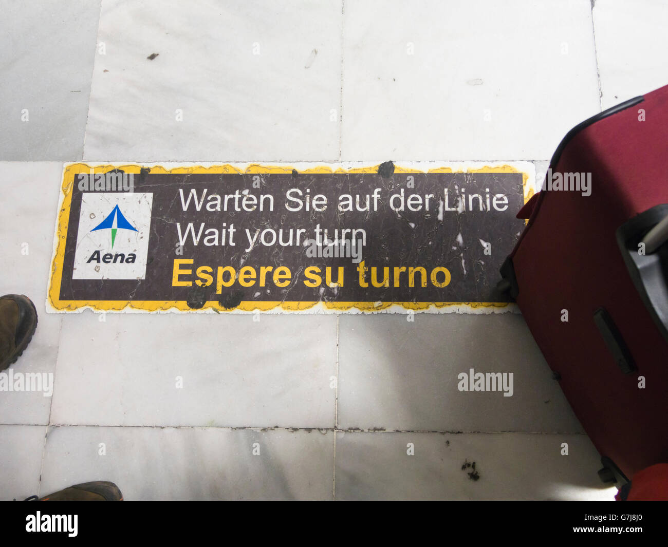 Warten Sie an der Reihe, in drei Sprachen auf dem Boden der Check-in-Line in einem spanischen Flughafen nach Hause aus dem Urlaub melden Stockfoto