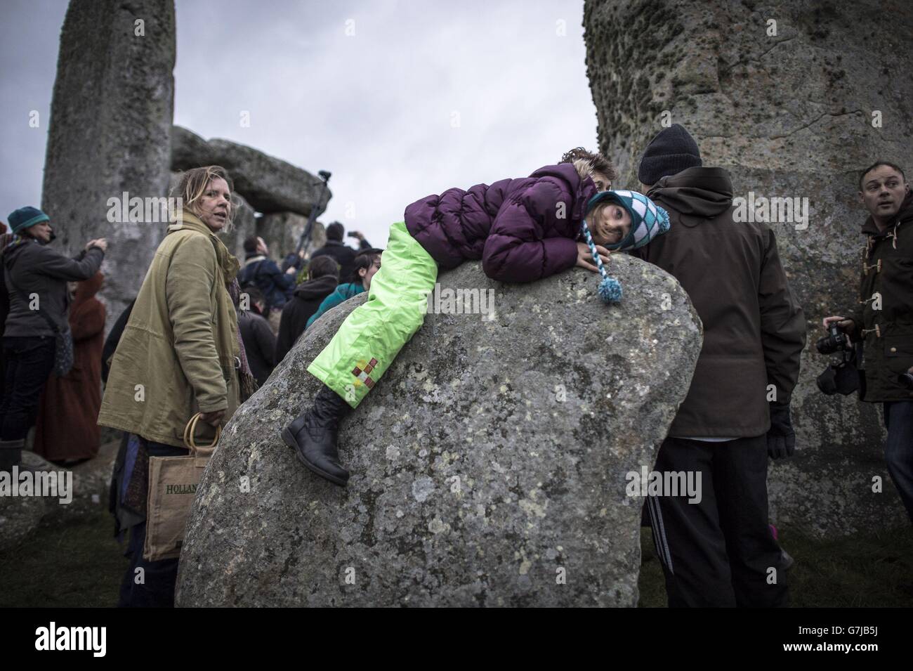 Ein Mädchen legt sich auf einen Stein in Stonehenge, Witshire, wo sich die Menschen versammeln, um die Wintersonnenwende zu feiern. Stockfoto