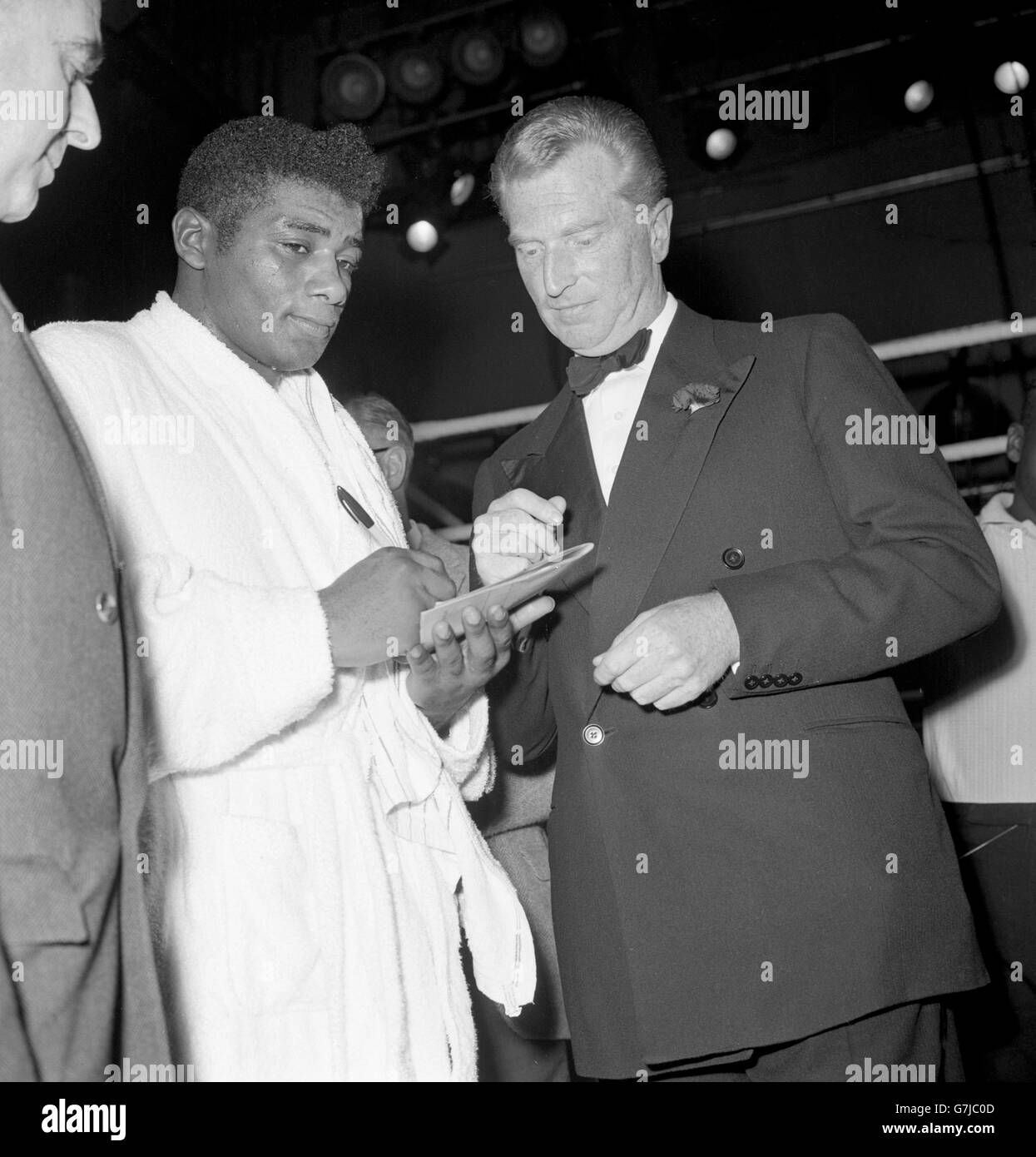 Der Weltmeister Floyd Patterson aus Amerika unterzeichnet sein Autogramm für den Mann, der ihn gerade interviewt hat, John Freeman (r). Der Boxer hatte gerade zusätzlich zum Interview eine Ausstellung gegeben. Stockfoto