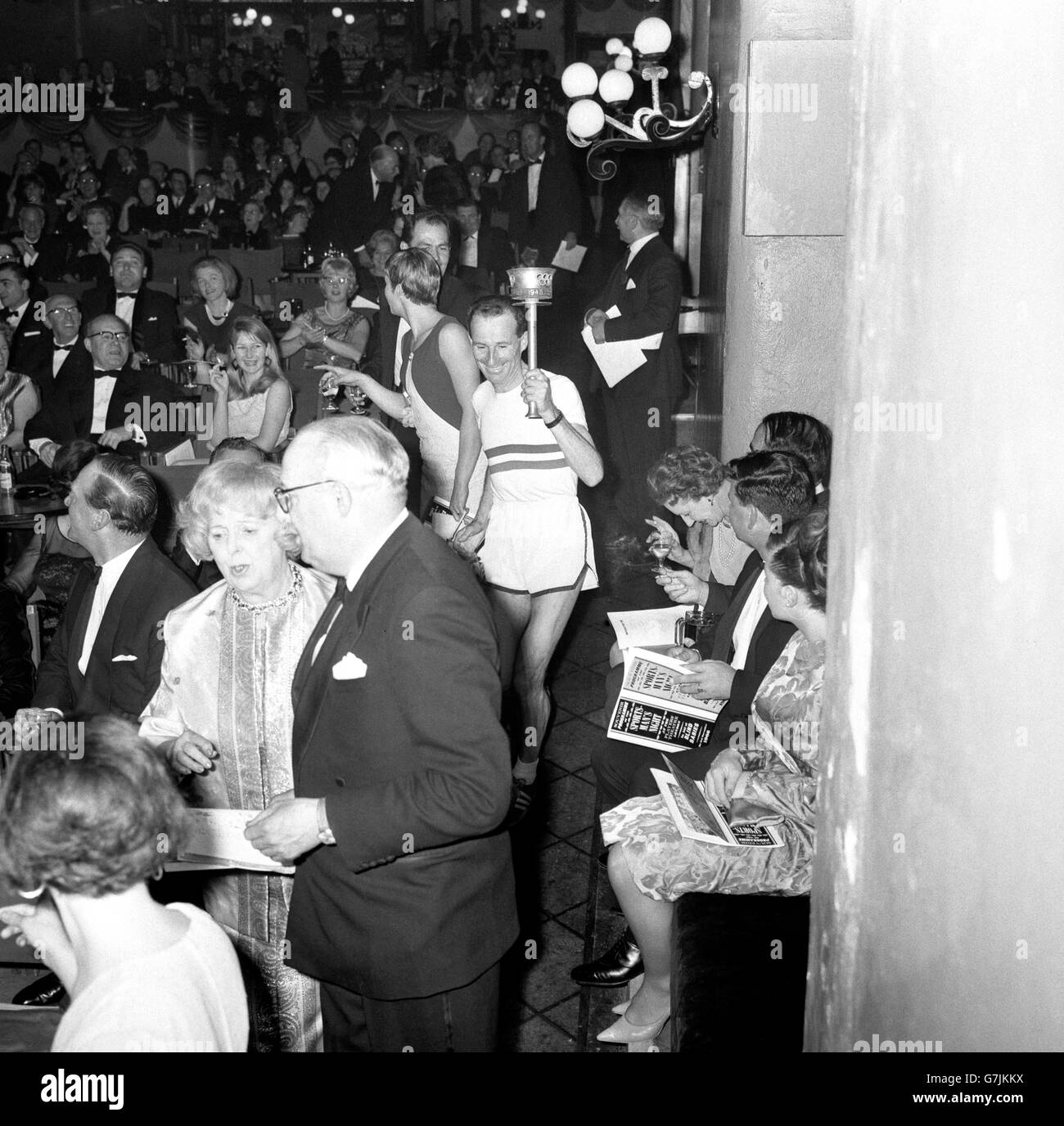 Jim Hogan, Gewinner des 26-Meilen-Marathons bei den Europameisterschaften in Budapest, läuft im Players' Theatre in der Villiers Street, London, an einem Gang entlang. Er kam mit einer Fackel an, nachdem er 18 Meilen von der Sunshine Home Nursery School in Northwood, Middlesex, gelaufen war. Mit seinem Auftritt eröffnete er eine Sonderaufführung der im viktorianischen Stil gehaltenen "Late Joys"-Musik-Hall-Show, die dem Sunshine Fund for Blind Babies and Young People zugute kam. Stockfoto