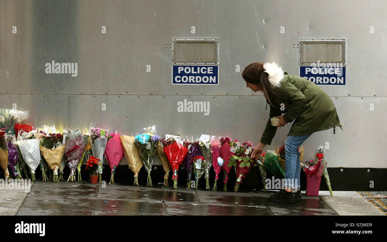 Eine Frau hinterlässt Blumen und Kerzen an einem Straßenblock in der Queen Street, in der Nähe des gestrigen Müllabsturzes in Glasgow. Stockfoto