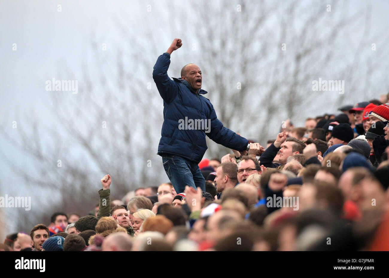 Ein Manchester United Fan steht über der Menge, als er auf seiner Seite während des FA Cup, Dritte Runde Spiel in Huish Park, Yeovil jubelt. Stockfoto