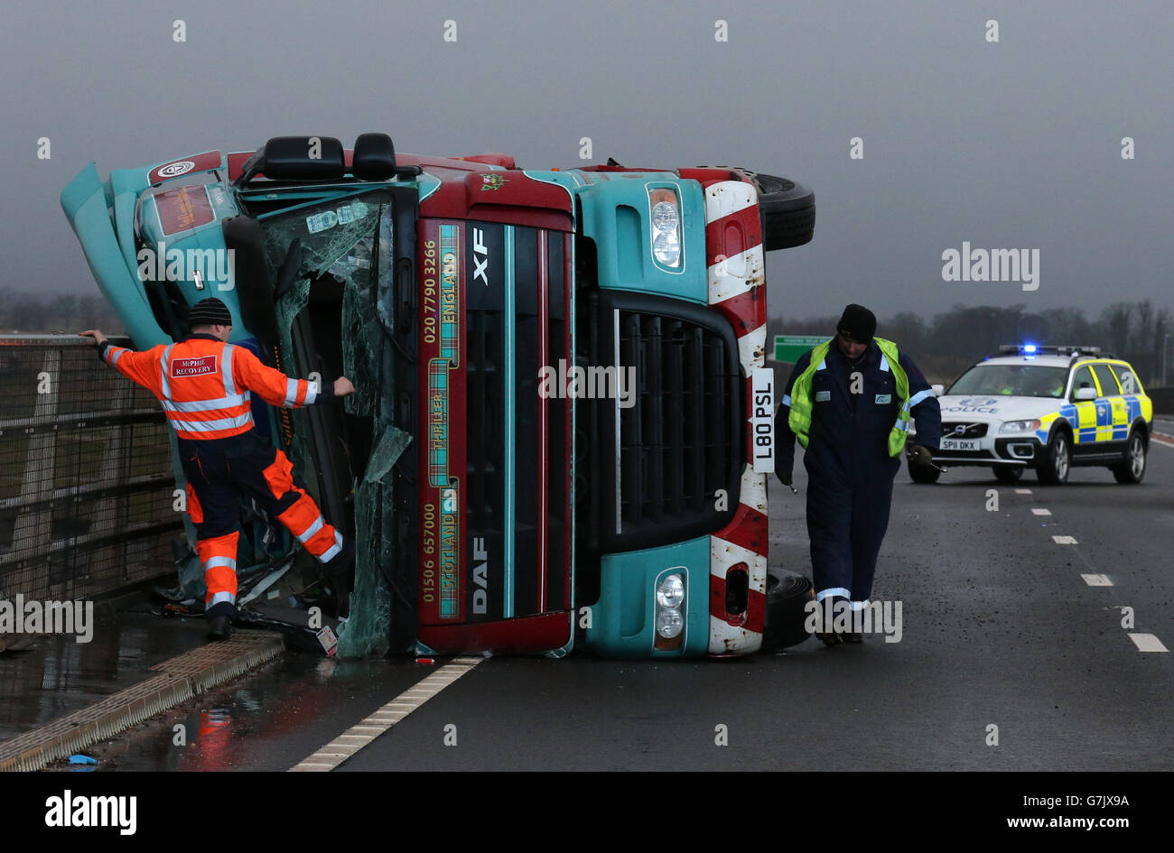 Ein Lastwagen liegt auf seiner Seite, nachdem er bei starkem Wind auf der Clackmannanshire Bridge über den Firth of Forth, Schottland, überwehen wurde, da starke Winde einen weiteren Tag der Störung der britischen Verkehrsnetze gebracht haben, während Warnungen vor heftigen Böen bestehen bleiben, Schnee und Eis über den Großteil des Wochenendes. Stockfoto
