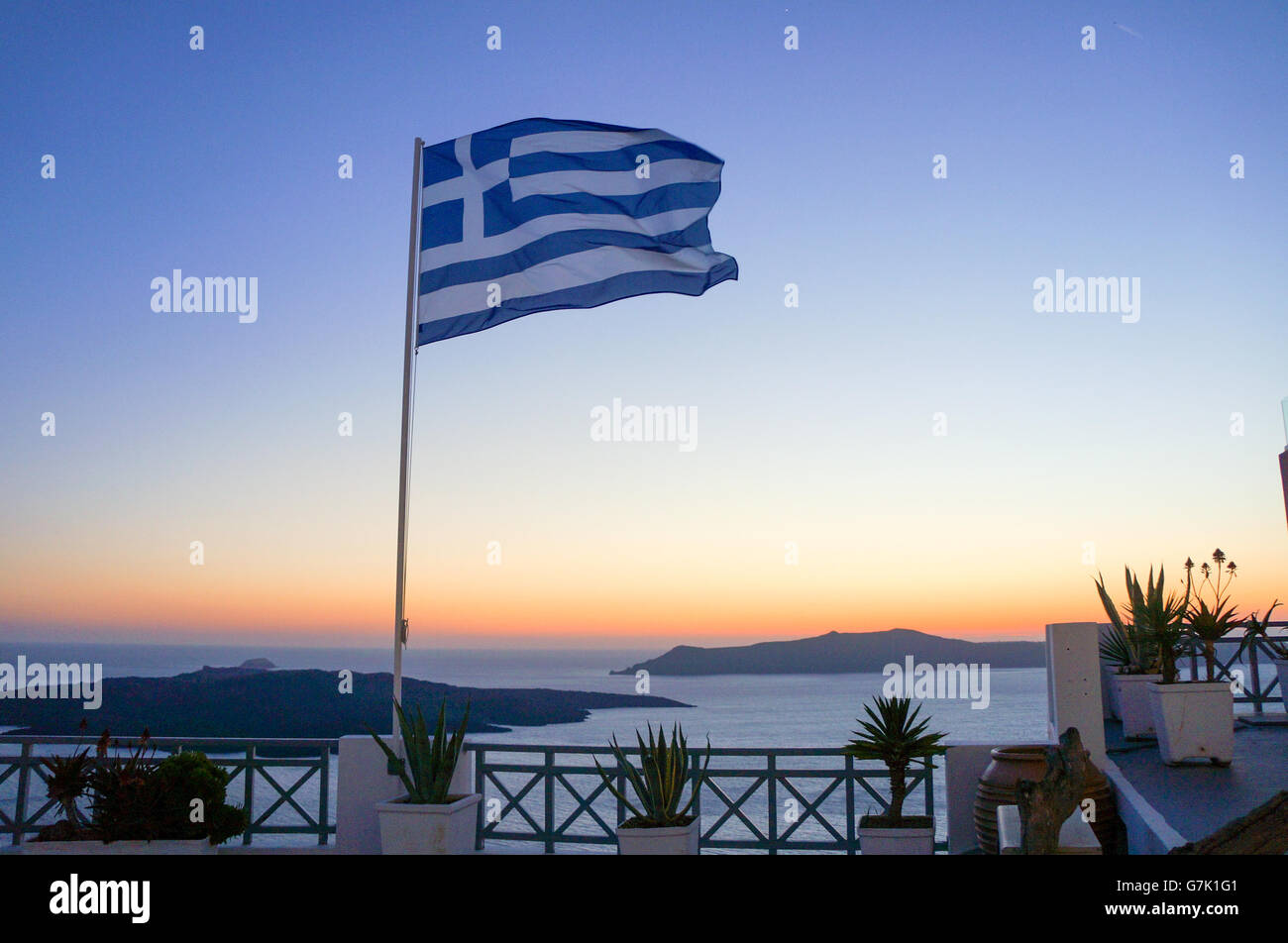 Griechische Flagge bei Sonnenuntergang am Meer gegen klarer Himmel Stockfoto