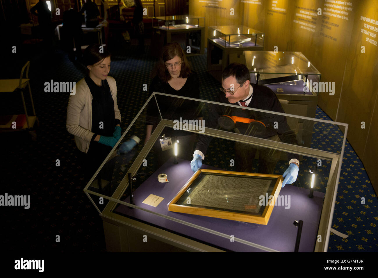 Die Salisbury Cathedral 1215 Kopie der Magna Carta wird in einem Schrank von Chris Woods (rechts), dem Direktor des National Conservation Service, installiert. Neben den anderen drei erhaltenen Originalumwingungen aus Pergament der Magna Carta anlässlich des 800. Jahrestages der Versiegelung der Magna Carta in Runnymede im Jahr 1215 im Robing Room der Queen im Houses of Parliament in London zu sehen. Stockfoto