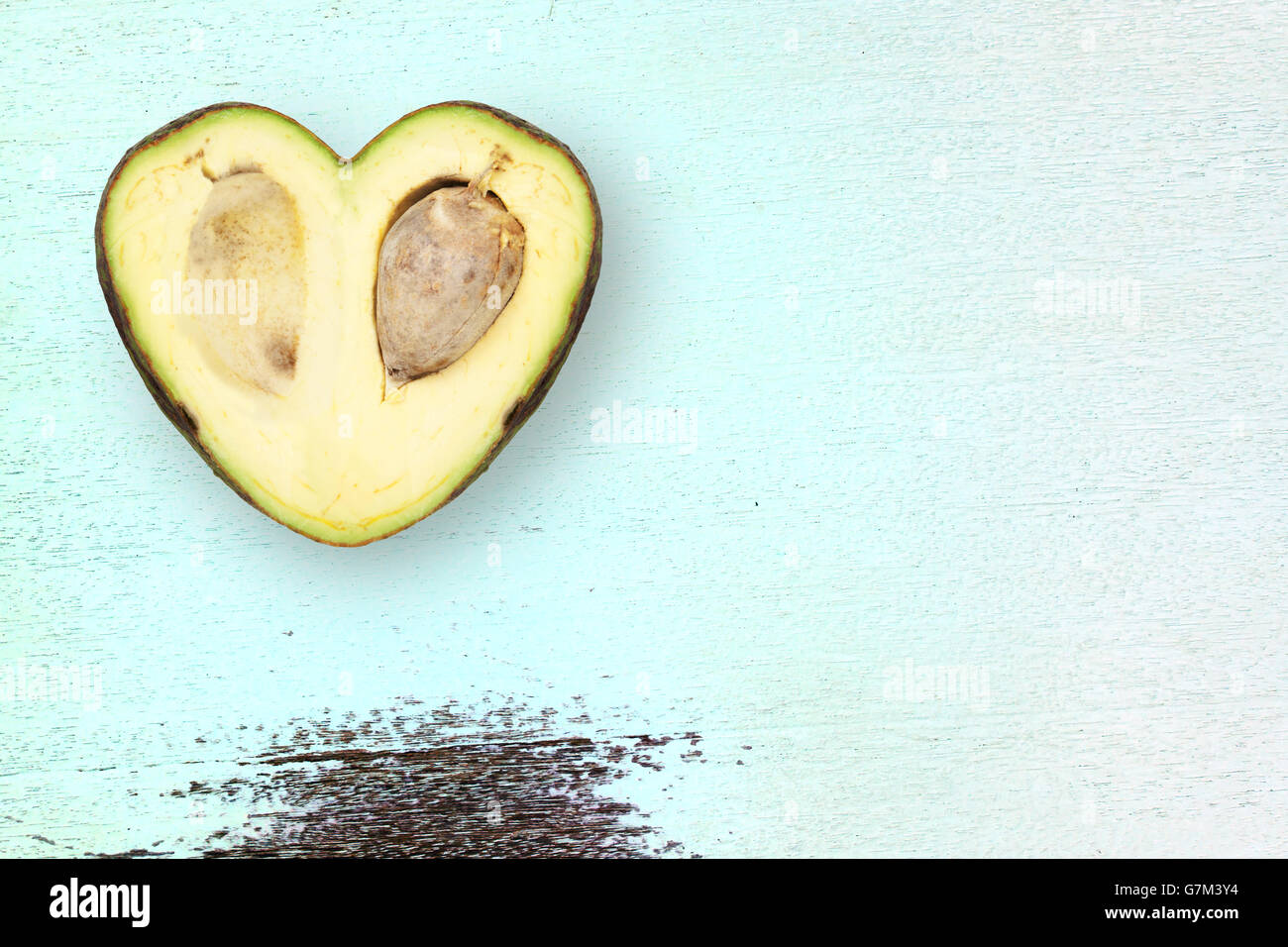 Avocado in der Form eines Herzens auf einem rustikalen Holztisch grün Stockfoto
