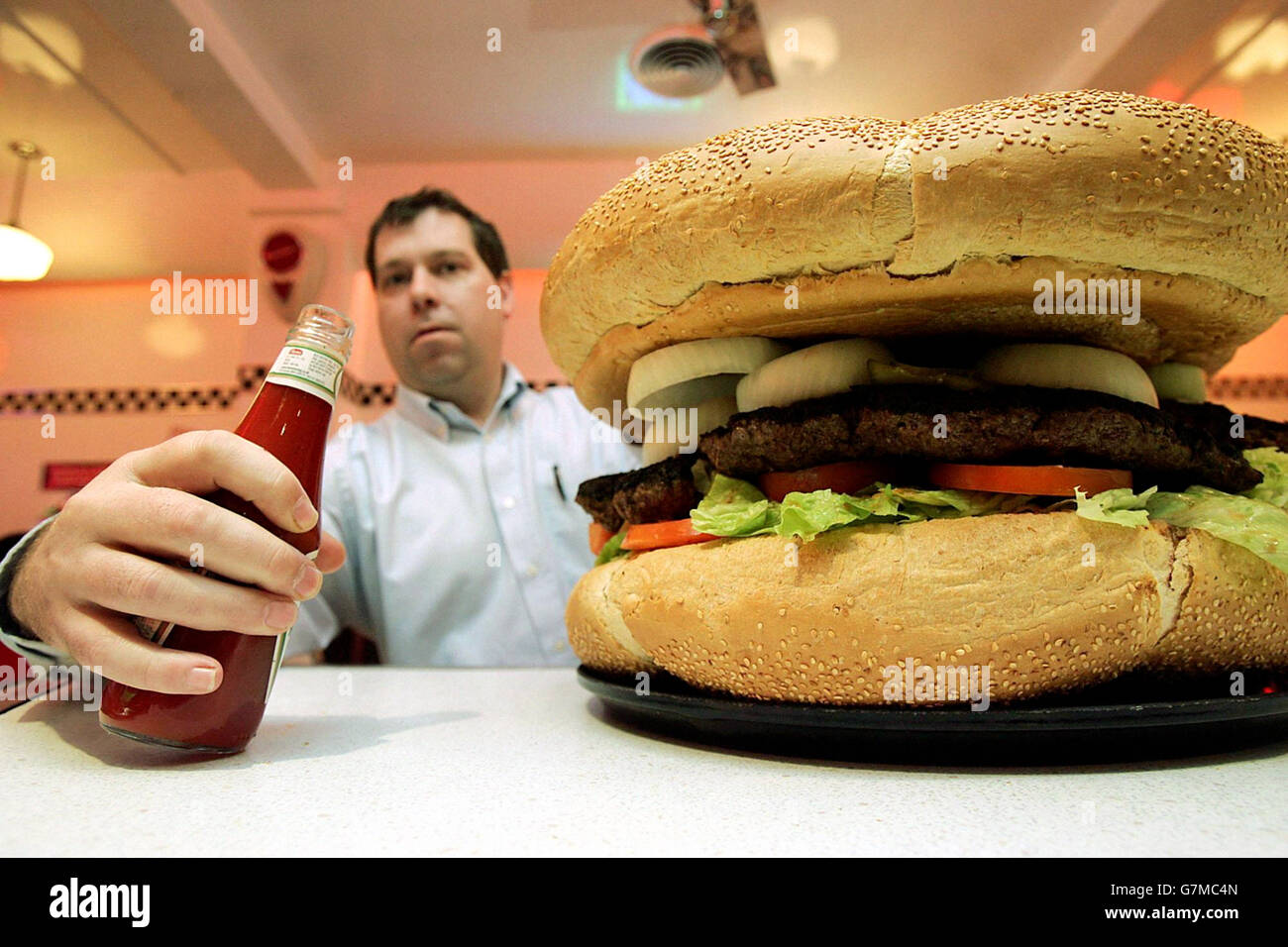 Ein Diner im Eddie Rockets Fast Food Restaurant in Dublin bereitet sich darauf vor, einen riesigen Burger mit 8 kg Fleisch zu probieren. Stockfoto