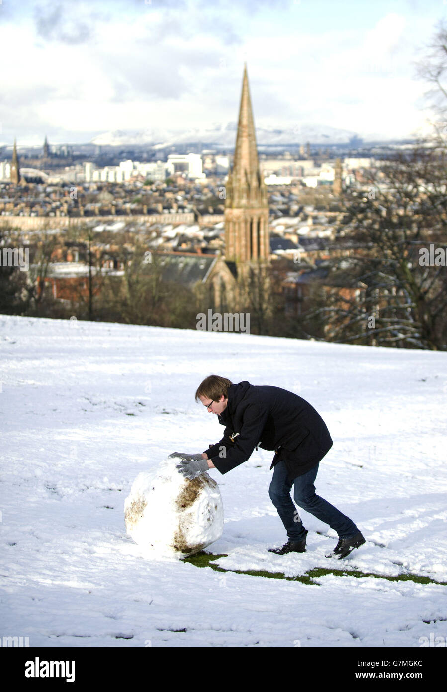 Ein Mann macht einen Schneemann in Glasgow Queen Park, wie das Met Office hatte eine Bernstein bewusst sein Wetterwarnung für einen Großteil von Schottland. Stockfoto