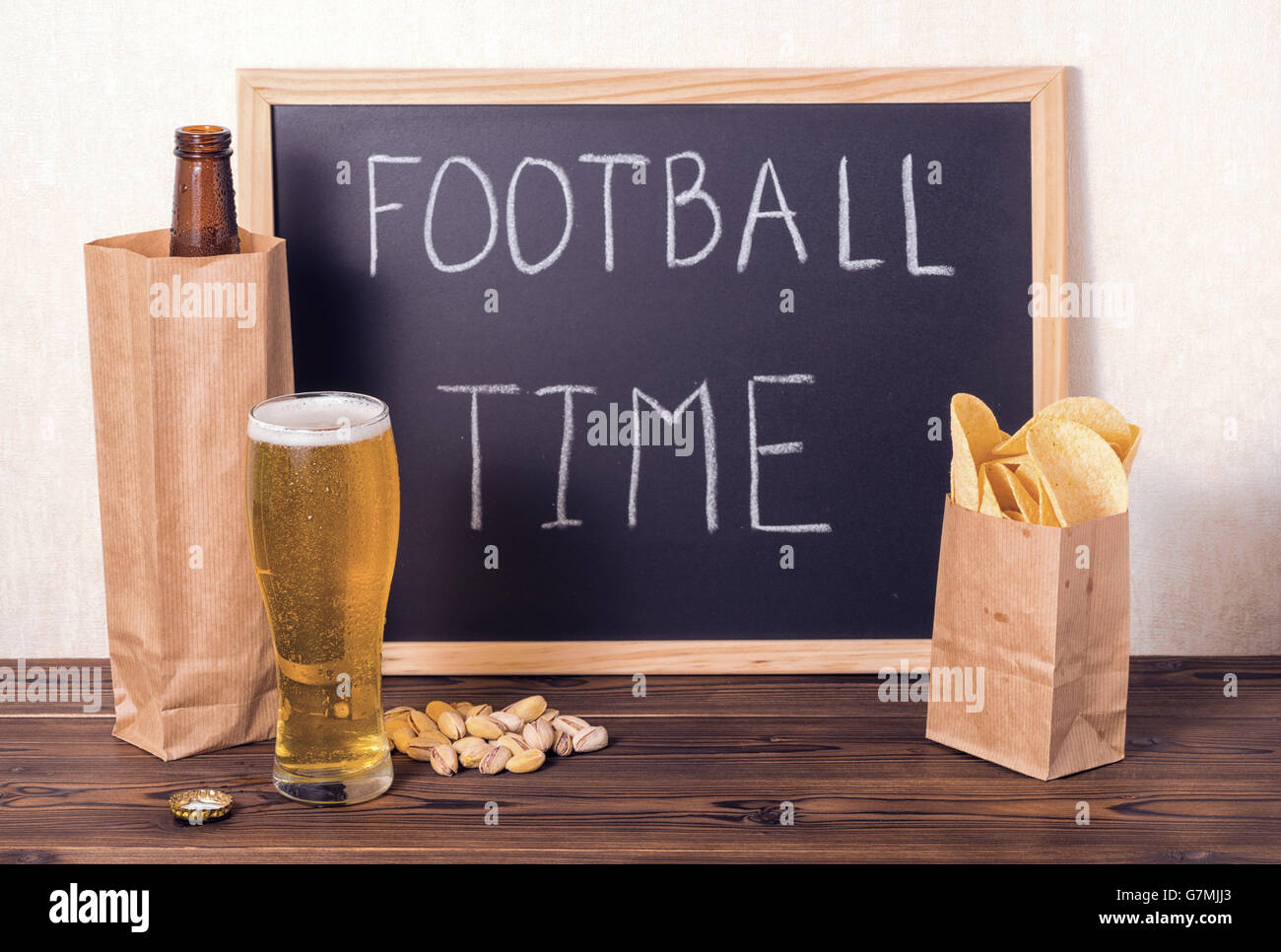 Einstellung der Bierflasche in braunem Papier Tasche, Glas, Chips, Pistazien und Handschrift Text Fußball Zeit geschrieben Fußball-fans Stockfoto