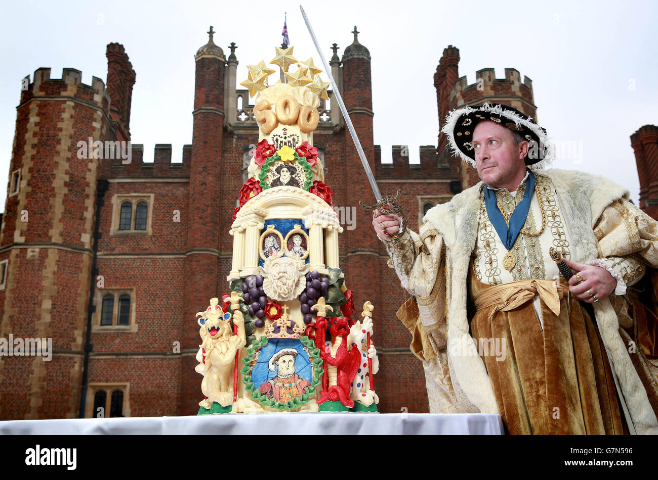 REDAKTIONELLE VERWENDUNG NUR König Henry VIII, gespielt von Chris Bailey, feiert den 500. Geburtstag von Hampton Court Palaces im Tudor Palast in East Molesey, Surrey, mit einem aufwändig detaillierten fünfstufigen Kuchen, der von Historic Royal Palaces aus Choccywoccydoodah in Auftrag gegeben wurde. Stockfoto