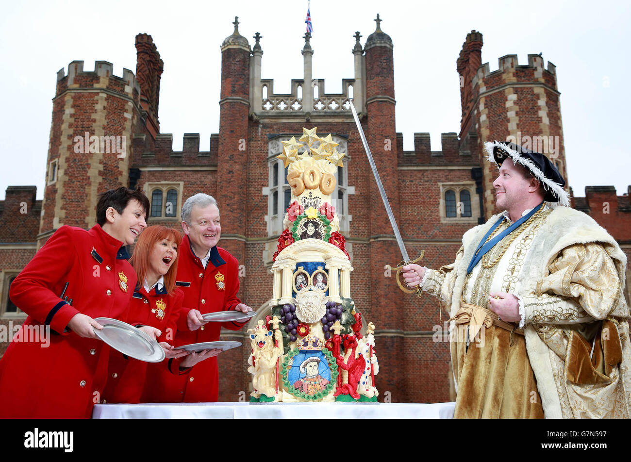 König Henry VIII, gespielt von Chris Bailey, mit Wächter - (von links nach rechts) Caroline Webb, Sheila Dunsmore und Richard Sewell, feiern den 500.Geburtstag des Hampton Court Palastes im Tudor Palast in East Molesey, Surrey, mit einem aufwendig detaillierten fünfstufigen Kuchen, der von Historic Royal Palaces aus Choccywoccydoodah in Auftrag gegeben wurde. Stockfoto