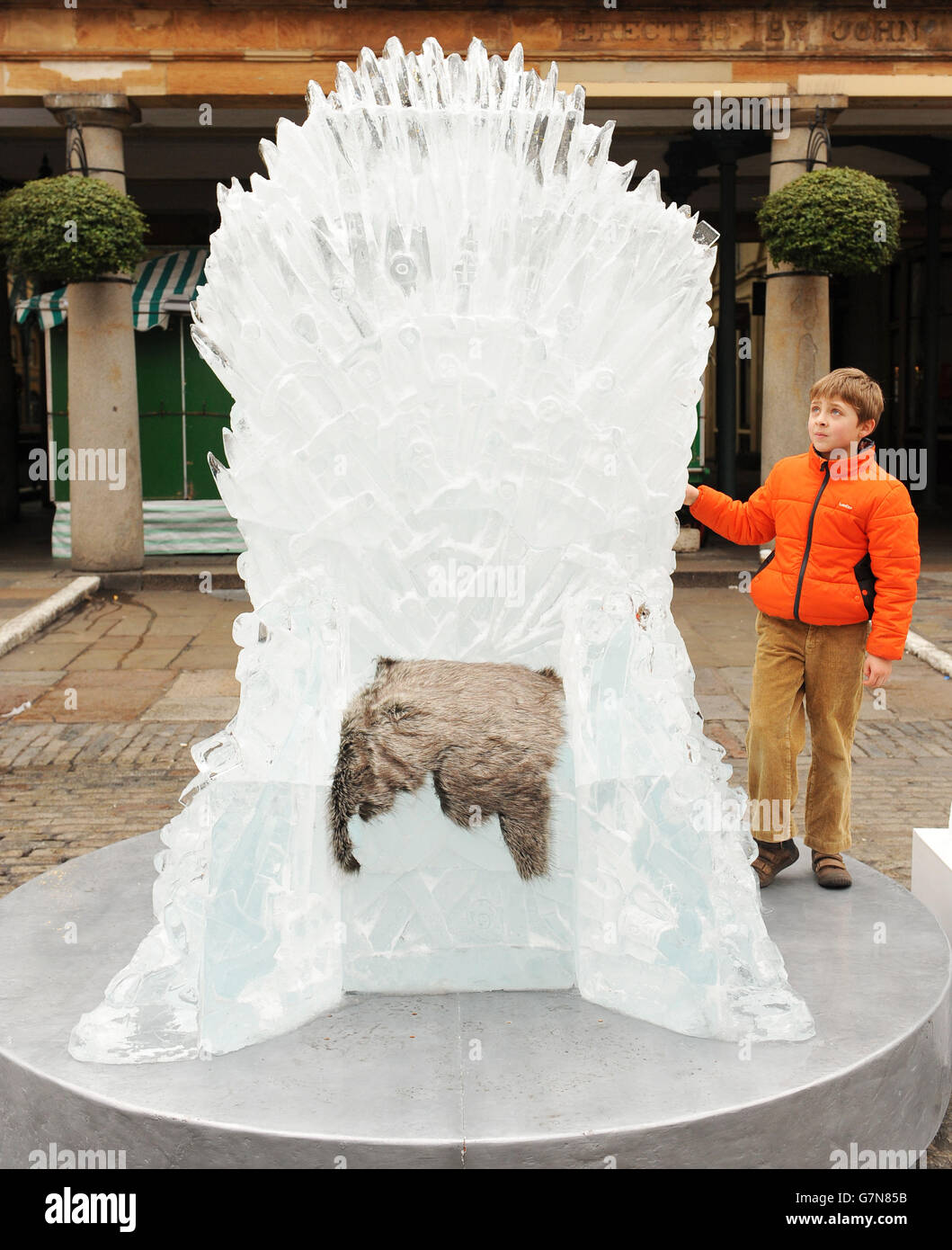Der achtjährige Ben Finn blickt auf einen Eiskunstlauf in lebensgroßer Größe, den Iron Throne, der in Covent Garden, London, ausgestellt wird, um den Start von Game of Thrones: The Complete Fourth Season zu feiern. Stockfoto