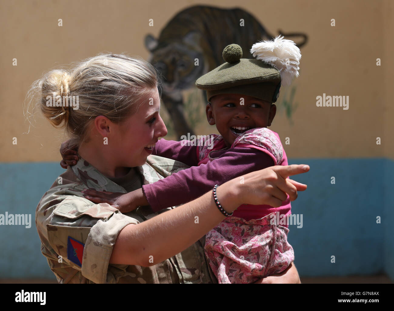 Private Jess Robshaw aus 2 Schotten, spielt mit einem Waisenkind, das ihr Tam O'Shanter trägt, während eines Besuchs im Nanyuki Kinderheim, um den Waisenkindern Geschenke als Soldaten des 2. Bataillons, des Royal Regiment of Scotland, zu spenden. Nehmen Sie an der Übung Askari Storm am Stadtrand von Nanyuki, Kenia, Teil. Stockfoto