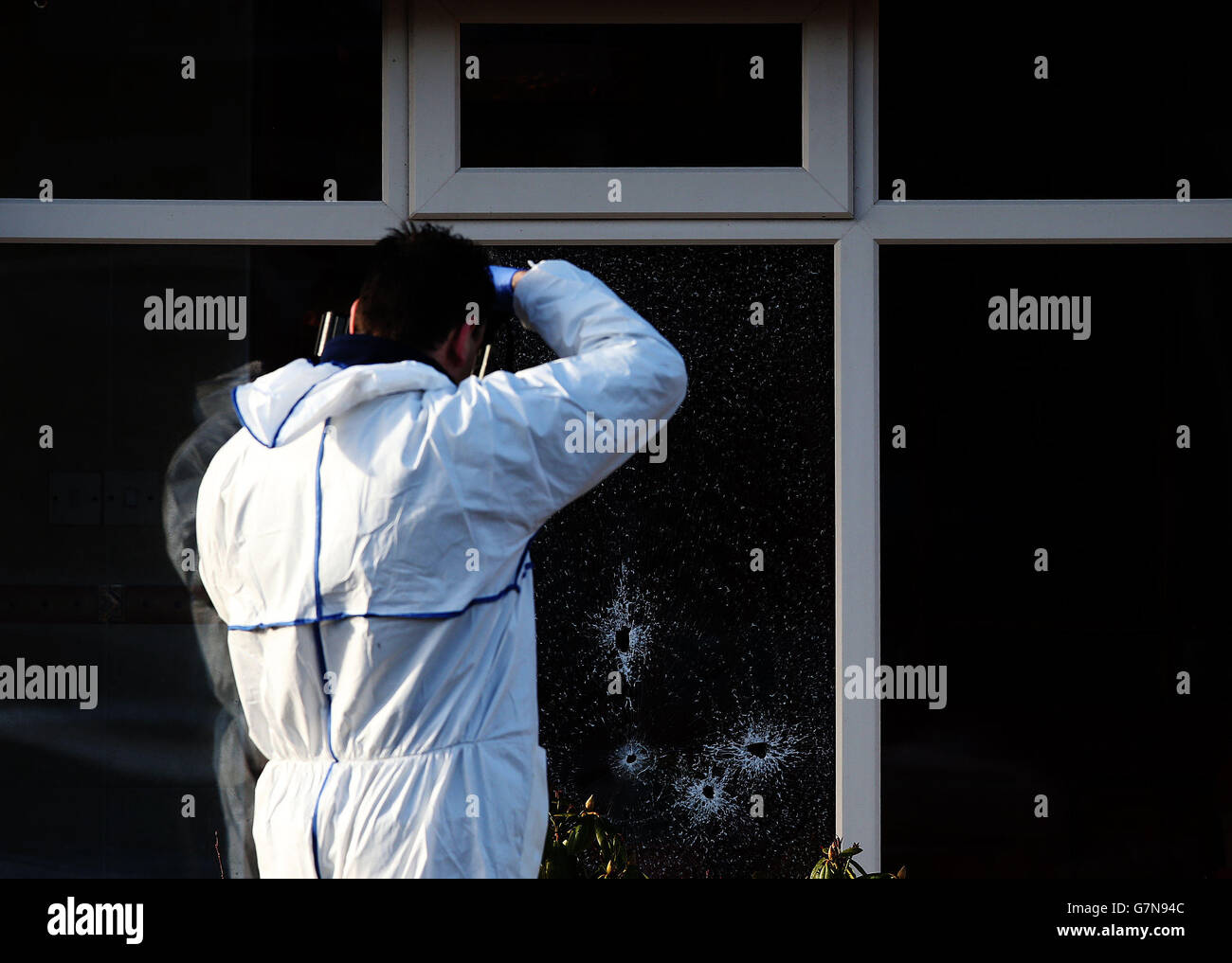 Ein Mitglied des Forensik-Teams von Garda fotografiert Einschusslöcher am Tatort auf der Harty Avenue, Walkinstown, wo ein Mann vor seinem Haus erschossen wurde. Stockfoto