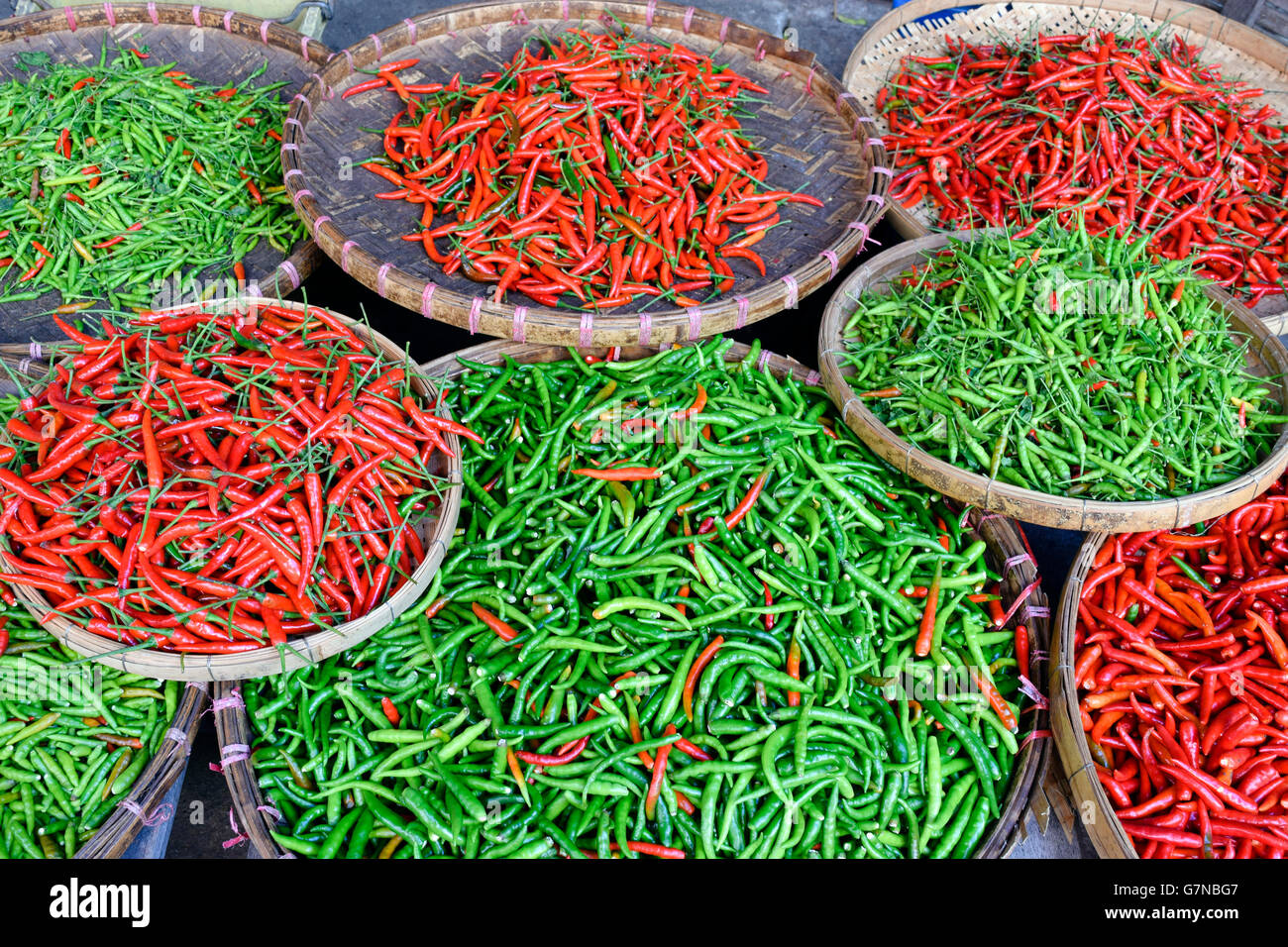 Eine Anordnung von roten und grünen Thai Chili Peppers in einem asiatischen Markt in Thailand. Stockfoto