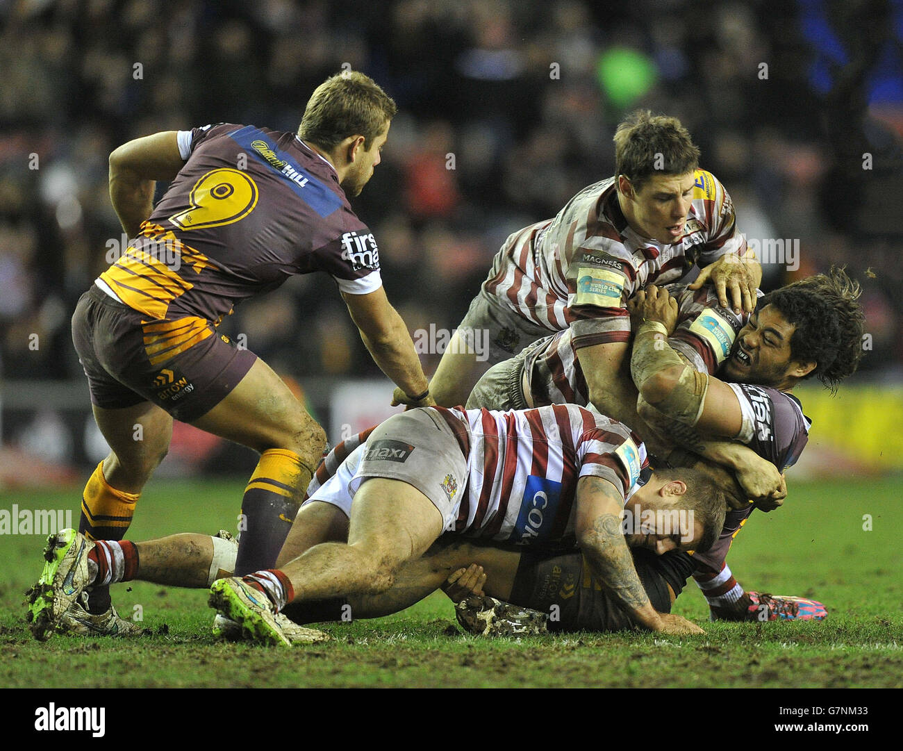 Josh McGuire von Brisbane Broncos wird im Wigan Stadium gegen Michael McIlorum und Joel Tomkins von Wigan Warriors während des Spiels der World Club Series angegangen. Stockfoto