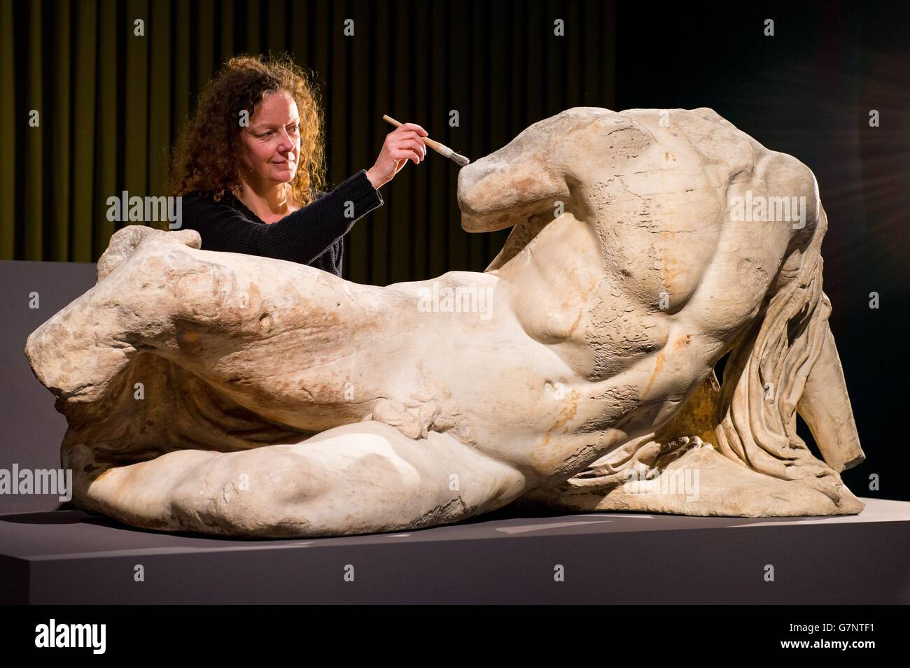 Die Senior Conservator Karen Birkhoelzer ist mit der Skulptur „The River God Ilissos“ von Phidias zu sehen, die Teil der Ausstellung Defining Beauty: The Body in Ancient Greek Art im British Museum, London, die am 26. März eröffnet wird. Stockfoto