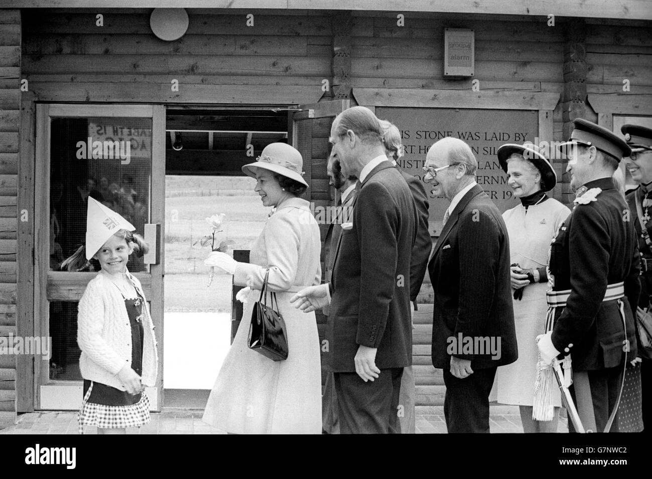 Der „Hattrick“ eines jungen Mädchens bietet der Königin ein amüsantes Zwischenspiel, als sie den Wildvogelpark in Washington besuchte, während ihre Silver Jubilee Tour durch den Nordosten fortgesetzt wird. Der Hut des Jungen rutschte aus, als sie der Königin eine Rose vorstellte. Mit der Königin sind Prinz Philip und Sir Peter Scott (ganz rechts). Stockfoto