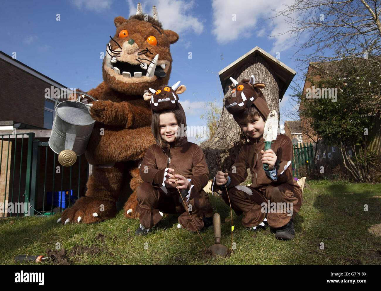 REDAKTIONELLE VERWENDUNG NUR der Gruffalo hilft den Schulkindern des 1. Jahrs Lucy Bayfield (links) und Mert De Sousa Vieira von der All Saints Church of England Primary School in Barnett, Nord-London, Bäume zu Pflanzen, als Teil der Kampagne von Yorkshire Tea mit einer Million Bäumen. Stockfoto