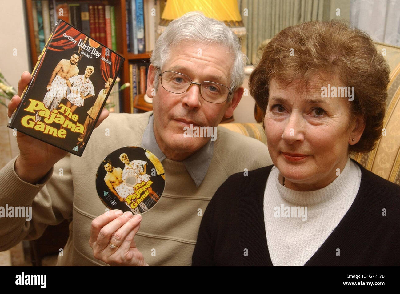 Alan und Anne Leigh-Browne halten bei sich zu Hause die DVD-Box "Pajama Game", während auf dem Fernsehbildschirm die ersten Titel eines Films mit entschieden "Erwachsenen"-Inhalten gezeigt werden. Stockfoto