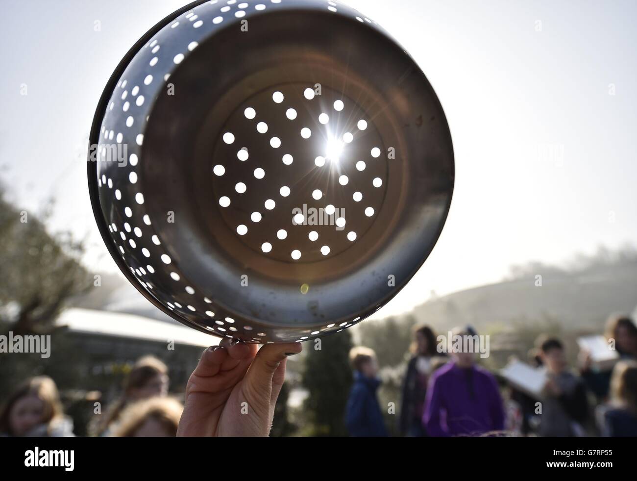 EDS HINWEIS: SONNENFILTER WURDE VERWENDET Menschen beobachten die Sonnenfinsternis durch einen Sieb über dem Eden Project in der Nähe von St. Austell in Cornwall. Stockfoto