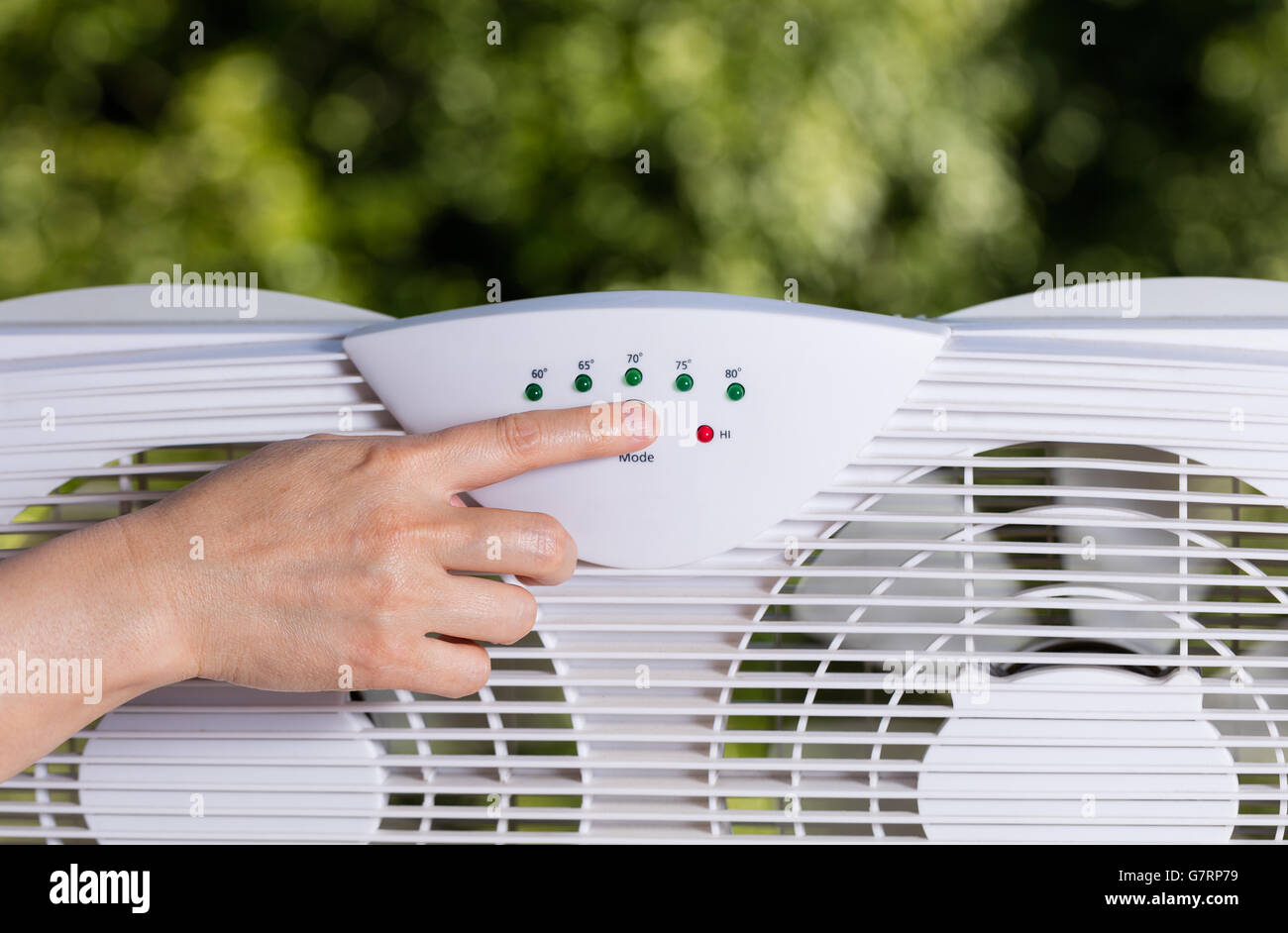 Hand-Auswahl-Temperatur auf zwei-Wege-Fenster-Fan in home-Fenster mit unscharfen, Bäume im Hintergrund. Stockfoto