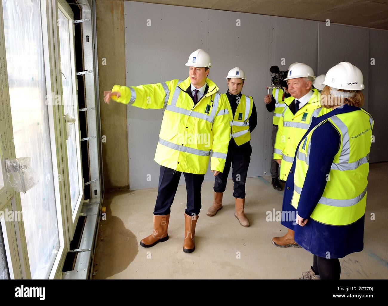 Premierminister David Cameron sieht mit dem CEO von Crest Building, Steve Stone (dritter links), die Bauarbeiten kurz vor dem Abschluss, während eines Besuchs auf einer Baustelle, auf der private Wohnungen in Isleworth im Westen Londons gebaut werden. Stockfoto