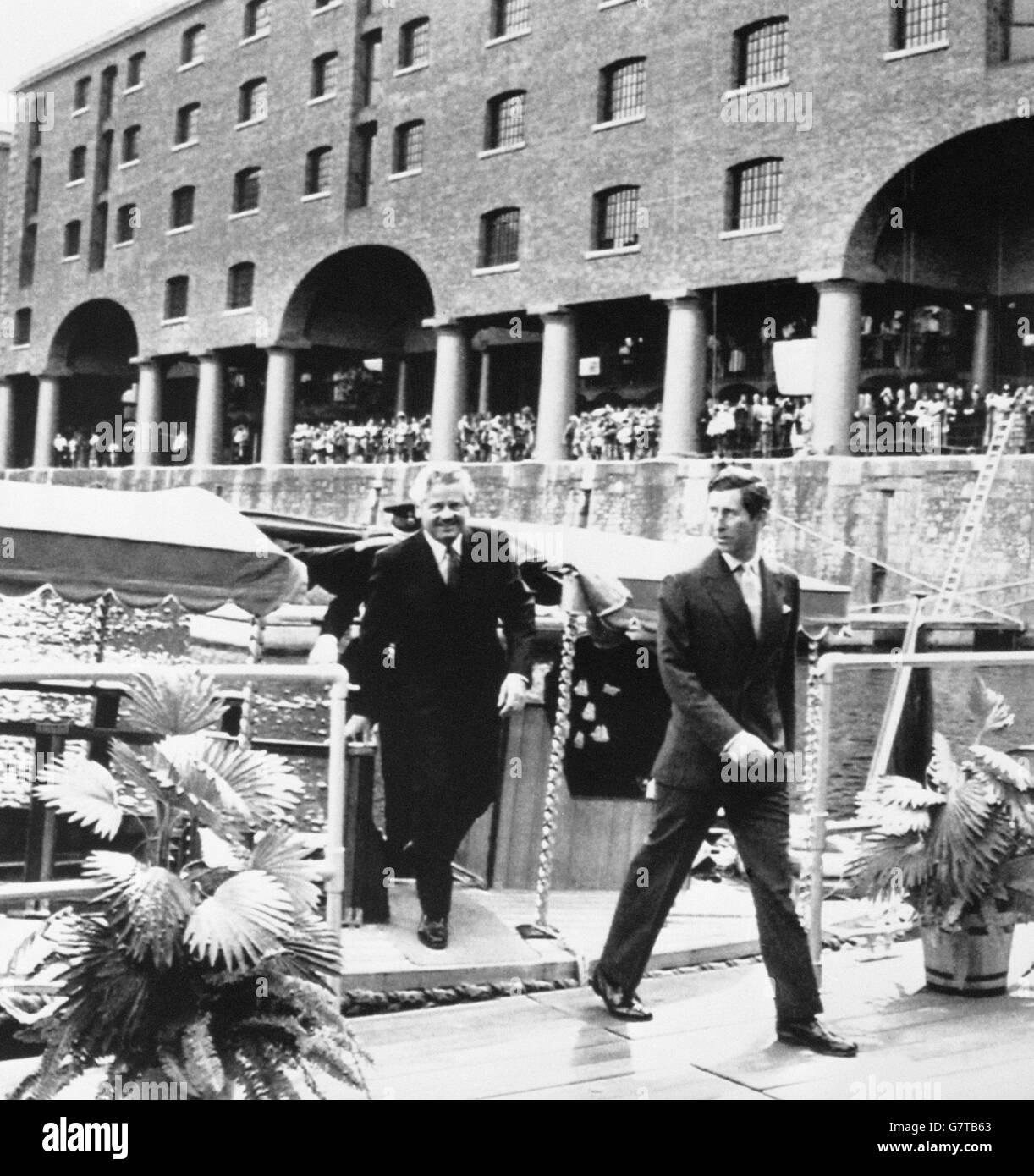 Der Prinz von Wales tritt 142 Jahre nach der Eröffnung durch seinen Urgroßvater aus einer Barge in Liverpools Albert Dock. Der Prinz öffnete das Dock zum zweiten Mal und eröffnete die neue Tate Gallery. Ihm folgt Philip Carter, Chairman der Merseyside Development Corporation. Stockfoto