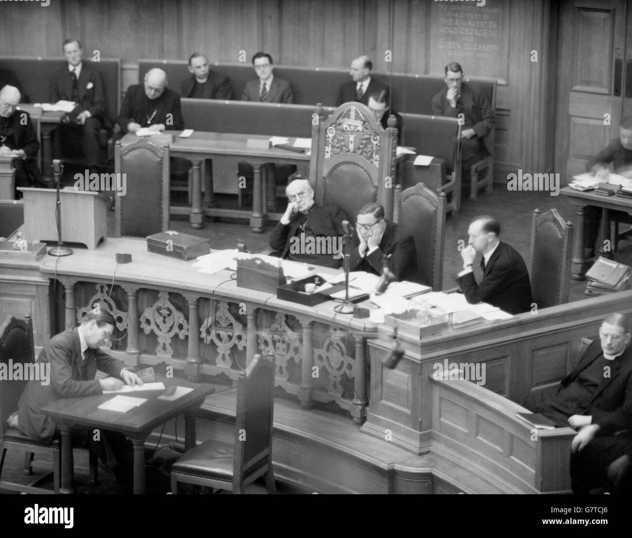 Der Erzbischof von Canterbury, Dr. Geoffrey Fisher, lehnt sich auf seinem Stuhl zurück und hört mit unerschütterlicher Konzentration einem Redner auf der Kirchenversammlung zu, der der Erzbischof den Vorsitz innehat, im Church House, Westminster, London. Tief in Gedanken mit dem Gesicht in den Händen ist Herr J. A. Guillum Scott, Sekretär der Kirchenversammlung. Vorschläge für bessere Renten für Witwen von Geistlichen gehörten zu den Themen, die diskutiert wurden. Stockfoto Der Erzbischof von Canterbury, Dr. Geoffrey Fisher, lehnt sich auf seinem Stuhl zurück und hört mit unerschütterlicher Konzentration einem Redner auf der Kirchenversammlung zu, der der Erzbischof den Vorsitz innehat, im Church House, Westminster, London. Tief in Gedanken mit dem Gesicht in den Händen ist Herr J. A. Guillum Scott, Sekretär der Kirchenversammlung. Vorschläge für bessere Renten für Witwen von Geistlichen gehörten zu den Themen, die diskutiert wurden. Stockfoto