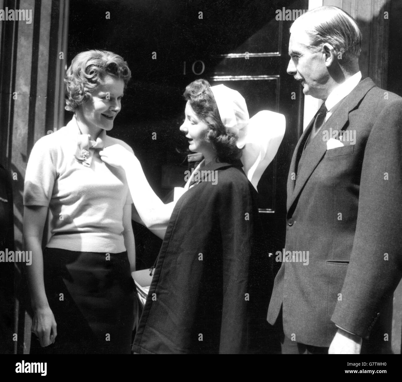 Der britische Premierminister Sir Anthony Eden sieht zu, wie seine Frau ihre Rote-Kreuz-Flagge von Miss Pauline Allison erhält, die die Downing Street 10 mit ihrem Flaggentablett und ihrer Sammelbox für den Fahnentag der British Red Cross Society anrief. Pauline ist Mitglied der Zweigstelle der Society im County of London und lebt in Stamford Hill. Stockfoto