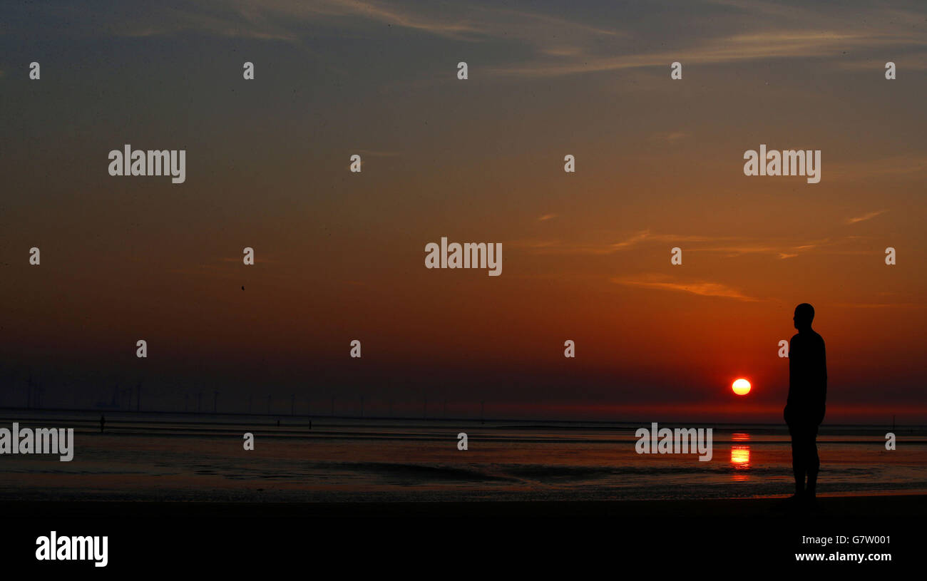 Die Sonne geht gestern Abend über einem der Iron Men, Teil der Another Place Installation von Antony Gormley, in Crosby Beach, Merseyside, unter. Stockfoto